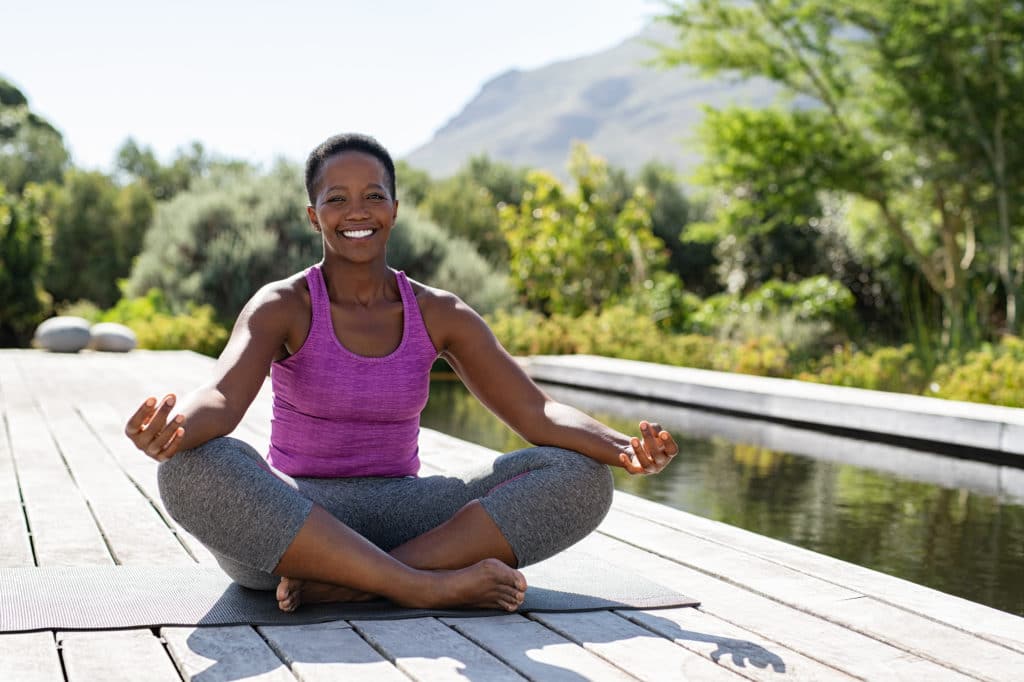 Smiling Woman in Meditative Pose | Medicare Plan Finder